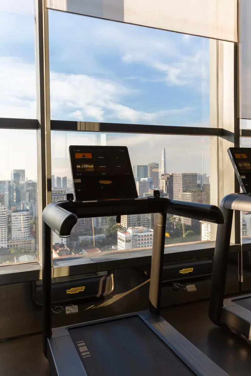 Máy chạy bộ đặt sát mặt kính phòng gym The Marq, phía ngoài là toà Bitexco
