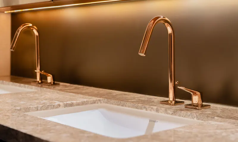 Vòi lavabo màu đồng hồng trên mặt đá cẩm thạch trong phòng tắm The Marq