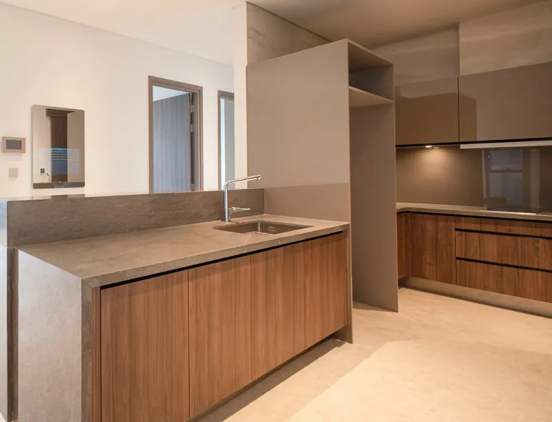 Bếp căn 4 phòng ngủ The Marq với đảo bếp mặt đá và tủ bếp veneer gỗ óc chó